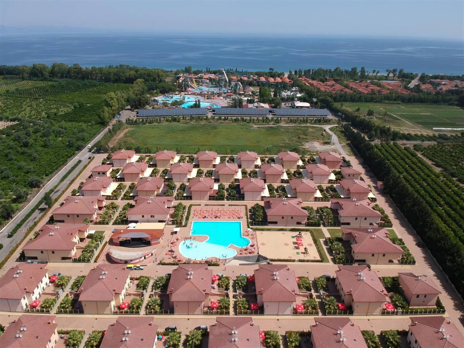 Vista aerea del Villaggio Afrodite con piscina, villette e mare sullo sfondo